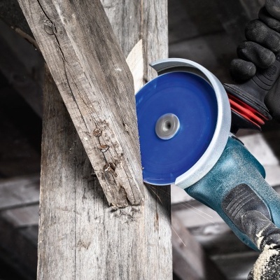 Esmeril angular a cortar madeira com lâmina azul em ambiente rústico