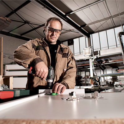 Homem a usar furadeira numa oficina industrial