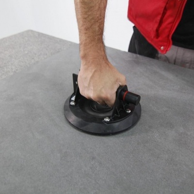 Ventosa preta com alça vermelha usada sobre superfície cinza