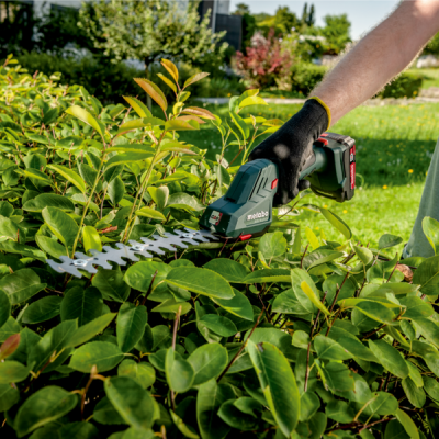 Tesoura elétrica de podar Metabo a cortar arbusto verde em jardim