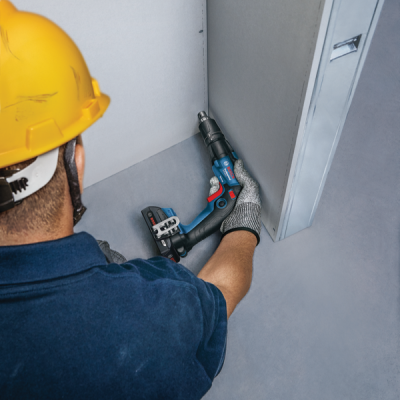 Pessoa a usar ferramenta elétrica Bosch para instalação em parede cinzenta