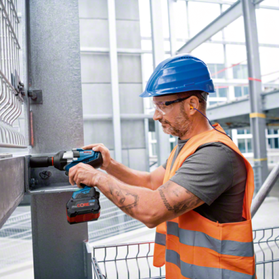 Trabalhador com equipamento de proteção a usar ferramenta elétrica num ambiente industrial