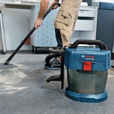 Aspirador portátil Bosch azul e cinza no chão com pessoa a aspirar