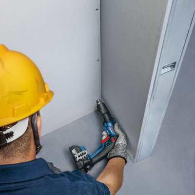 Trabalhador a parafusar placas de gesso com ferramenta elétrica
