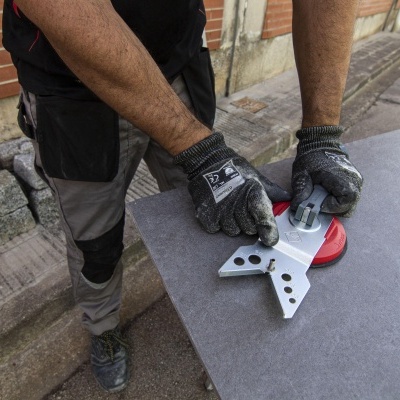 Mãos com luvas seguram ferramenta metálica sobre mesa cinza em ambiente exterior