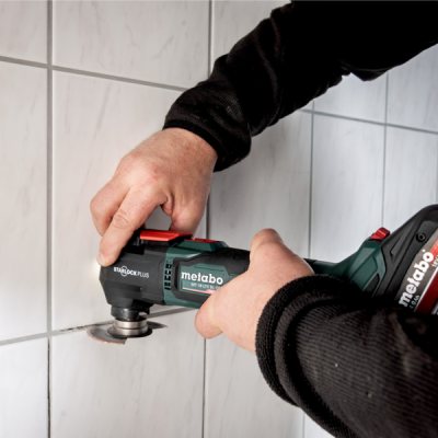 Ferramenta elétrica Metabo a cortar azulejos brancos numa parede