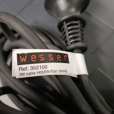 Cabo elétrico preto com etiqueta Wesser e ficha sobre azulejos cinza