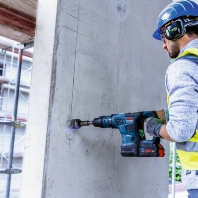Homem com equipamento de proteção a perfurar uma parede com ferramenta elétrica