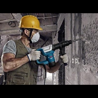 Homem com capacete amarelo usado ferramenta elétrica num ambiente de construção