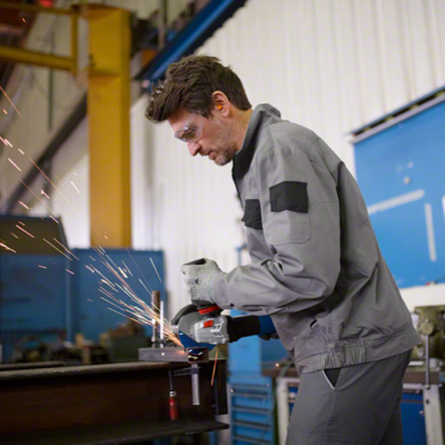 Homem a usar esmerilhadora elétrica com faíscas em ambiente industrial