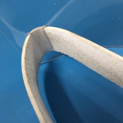 Alça de cinto ou correia clara com textura aveludada sobre fundo azul.