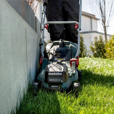 Corta-relva elétrico Metabo verde com relva e muro cinzento