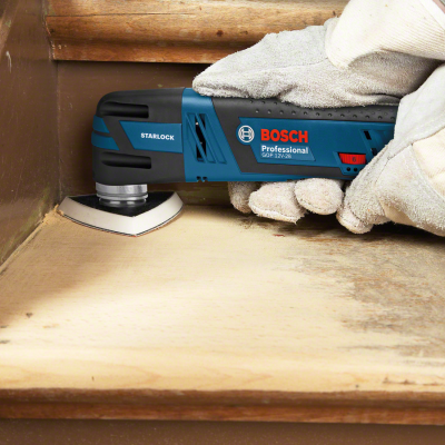 Ferramenta elétrica Bosch Professional azul escuro a lixar madeira clara com luvas brancas
