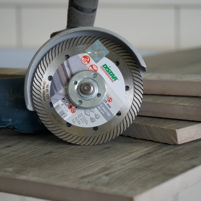Disco de corte para esmerilhadora com borda de diamante e etiqueta circular sobre superfície de madeira