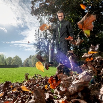 Pessoa a usar soprador de folhas preto para limpar folhas secas no jardim