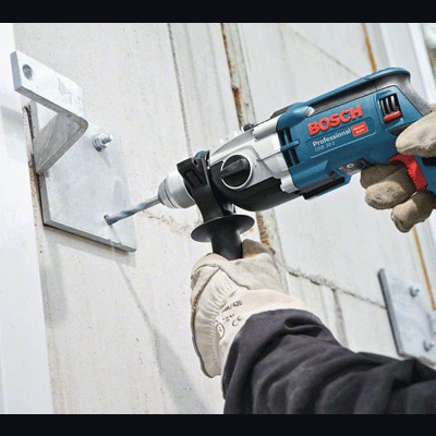 Pessoa a usar furadeira Bosch profissional com punho adicional a perfurar suporte metálico branco.