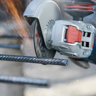 Rebarbadora elétrica cinza e vermelha a cortar barras de metal pretas com nervuras.