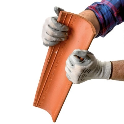 Telha cerâmica terracota segurada por mãos com luvas cinzentas sobre fundo branco