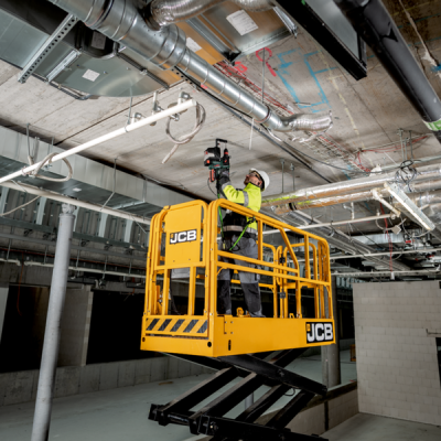 Plataforma elevatória amarela JCB com trabalhador a medir teto industrial