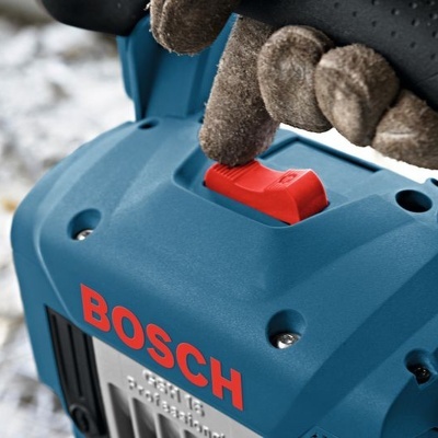 Botão vermelho de uma ferramenta Bosch azul sendo pressionado por uma luva cinzenta