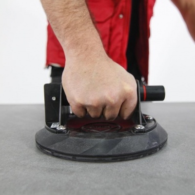 Ventosa preta manual com punho tubular numa superfície cinzenta