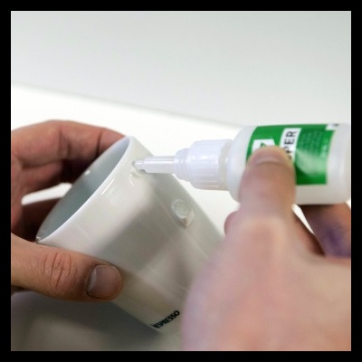 Aplicação de cola num copo branco de cerâmica Nespresso com fundo branco