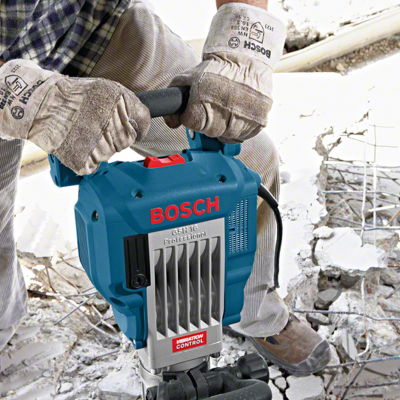 Martelo demolidor BOSCH azul e cinzento com luvas de proteção em ambiente de construção