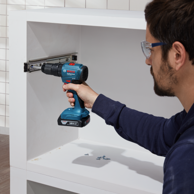 Parafusadeira Bosch Professional azul e preta 18V em uso num móvel branco