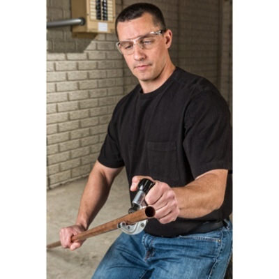 Homem usando óculos de proteção segurando tubo de cobre e alicate