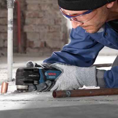 Pessoa a usar ferramenta elétrica Bosch em obra com luvas e óculos de proteção