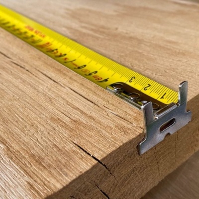 Fita métrica amarela a medir madeira clara com cortes visíveis