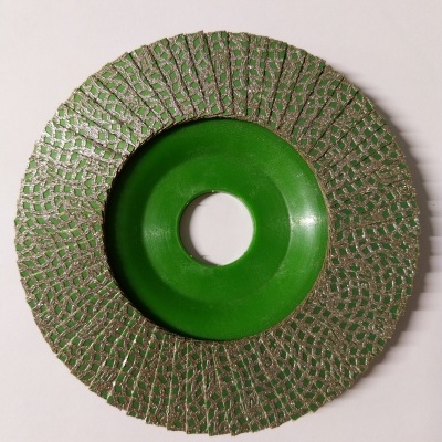 Disco de corte circular com núcleo verde e superfície metálica texturizada.