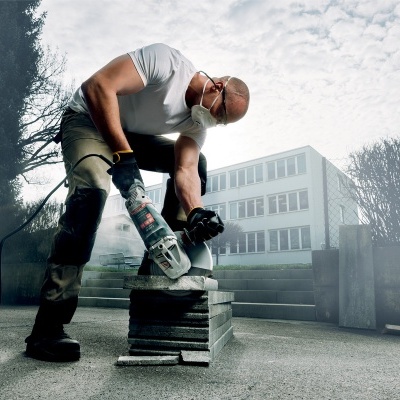 Homem a cortar pedras com esmerilhadora elétrica ao ar livre