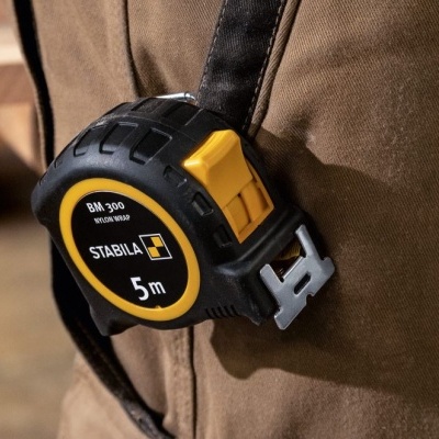 Fita métrica preta e amarela de 5m presa a um cinto castanho