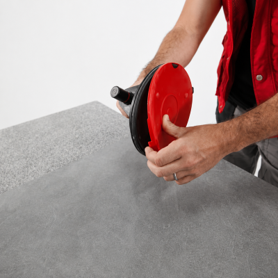 Homem com colete vermelho segurando equipamento de sucção preto e vermelho.