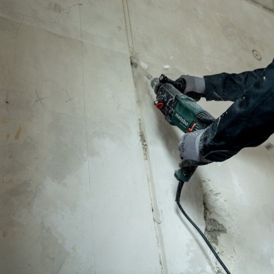 Pessoa usando ferramenta elétrica para trabalhar numa parede branca