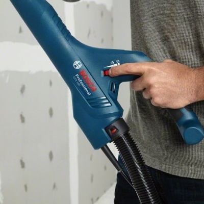Máquina de limpeza Bosch Professional azul escuro GVE 15 com mão ajustando seletor vermelho