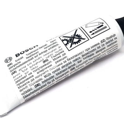 Tubo pequeno branco com tampa preta e texto em várias línguas