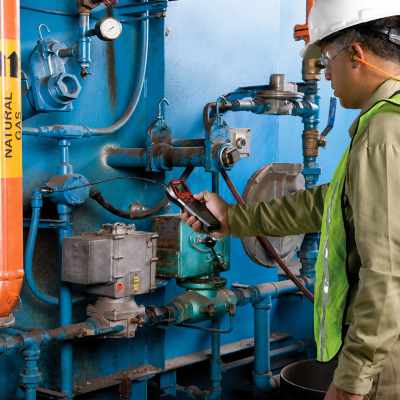 Trabalhador a utilizar dispositivo num sistema de tubagem azul com texto NATURAL GAS