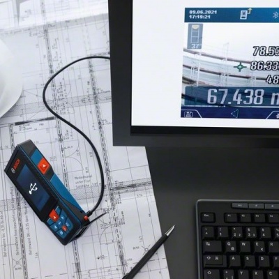 Dispositivo de medição a laser sobre plantas técnicas ao lado de capacete branco e teclado