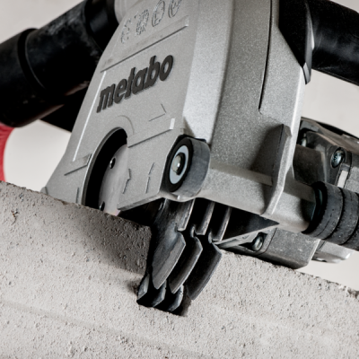 Ferramenta elétrica Metabo a cortar um bloco de cimento cinzento