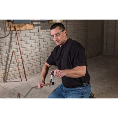 Homem usando ferramenta manual para tubo metálico em parede de tijolos cinzentos