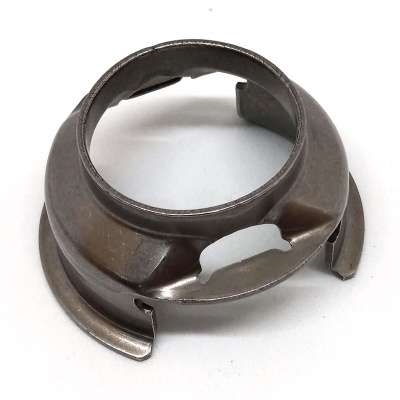 Peça metálica circular escura com recortes e superfície lisa sobre fundo branco