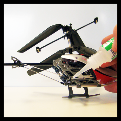 Mini helicóptero preto e vermelho a ser lubrificado com óleo