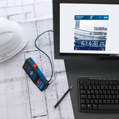 Dispositivo medidor Bosch digital sobre plantas arquitectónicas com capacete e monitor