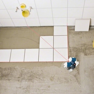 Piso em renovação com azulejos brancos e balde amarelo
