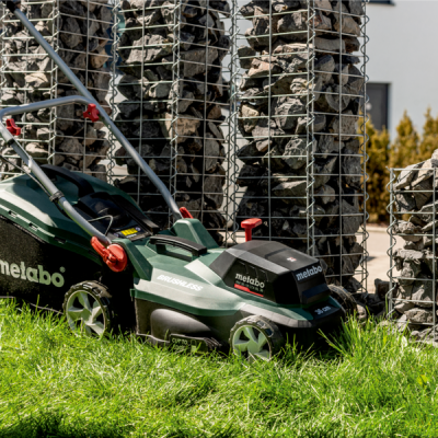 Cortador de relva elétrico Metabo verde com detalhes vermelhos na relva