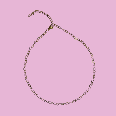 Colar dourado de corrente fina sobre fundo rosa