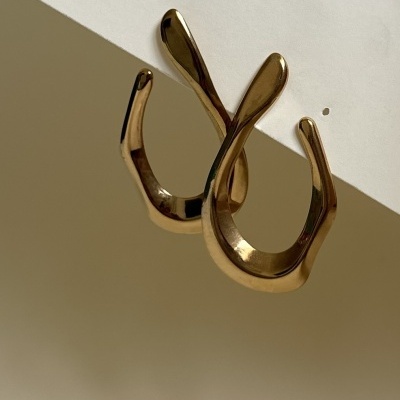 Brincos dourados em forma de laço sobre superfície clara