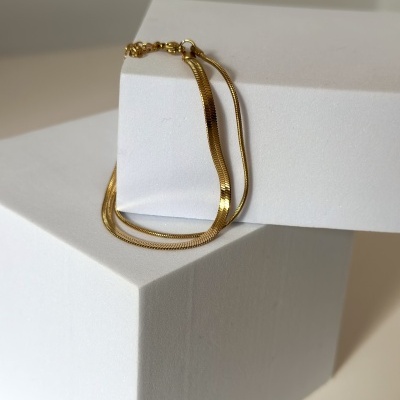 Colar dourado em superfícies brancas minimalistas